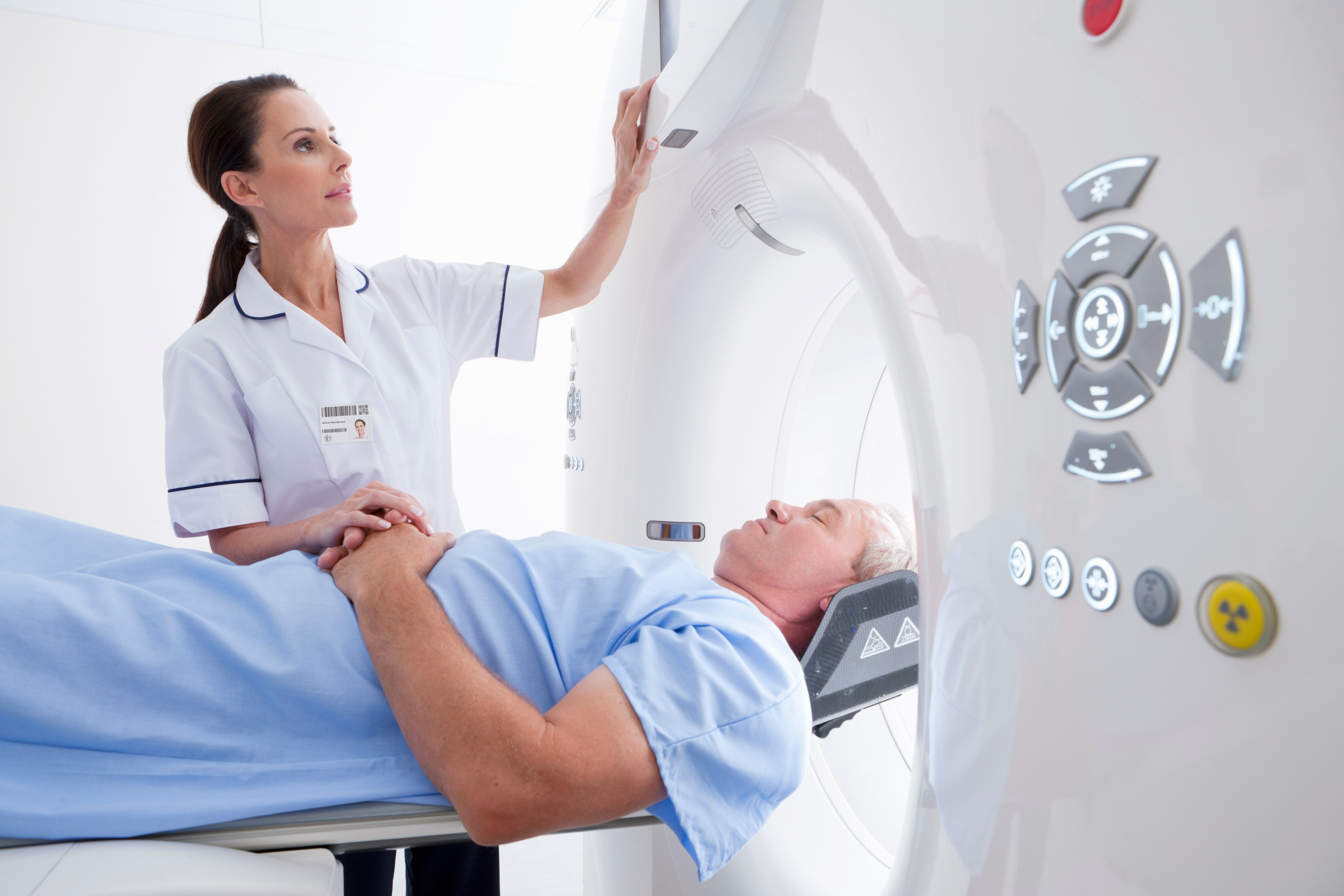 Patient being assisted into a CT Scan while medical professional ensures they are okay