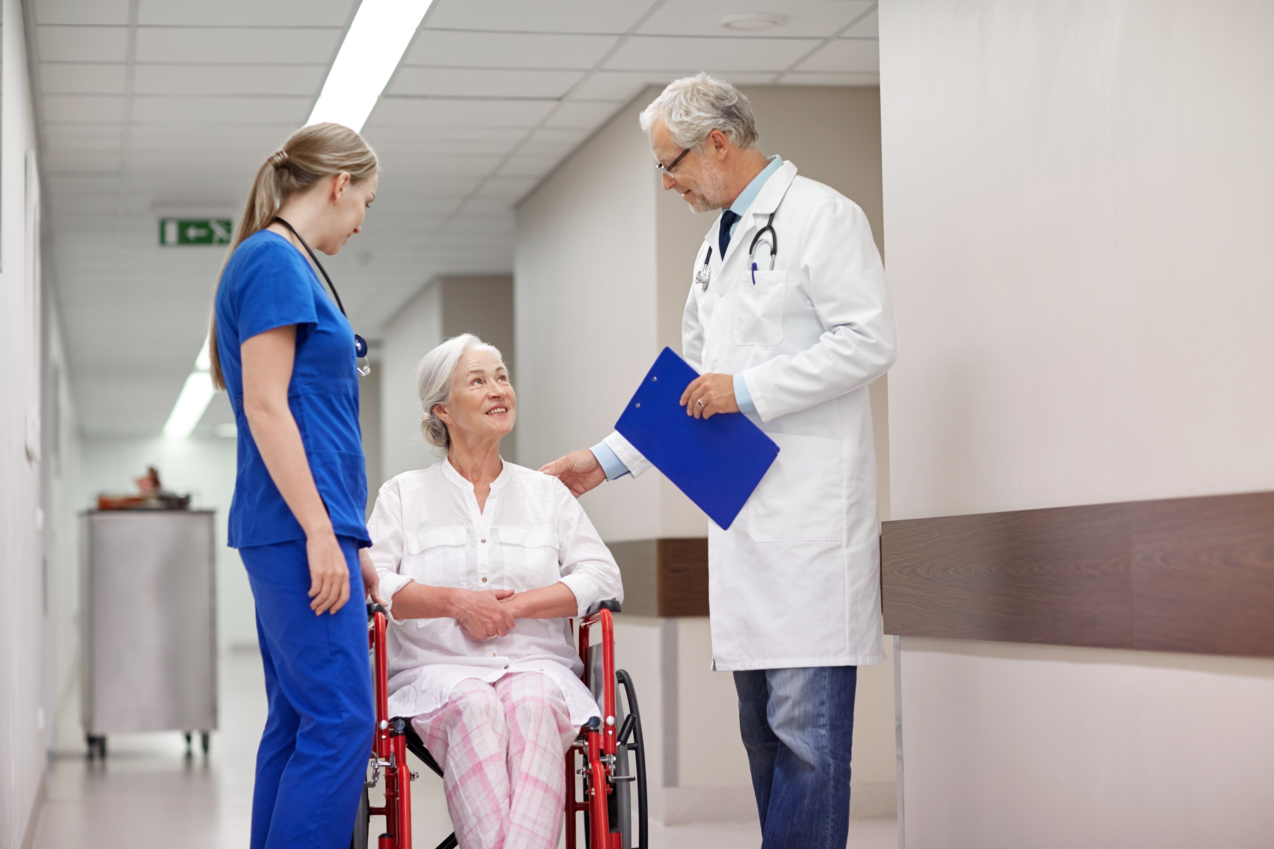 Elderly woman in a wheelchair getting care tips from her doctor after receiving medical care.